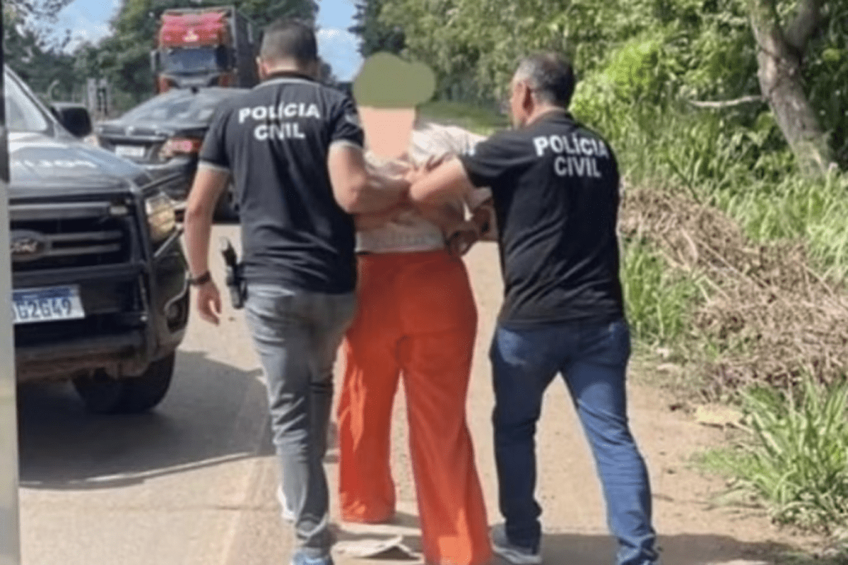 o femeie încătusată, care poartă pantaloni portocalii, este flncată de doi polițiști