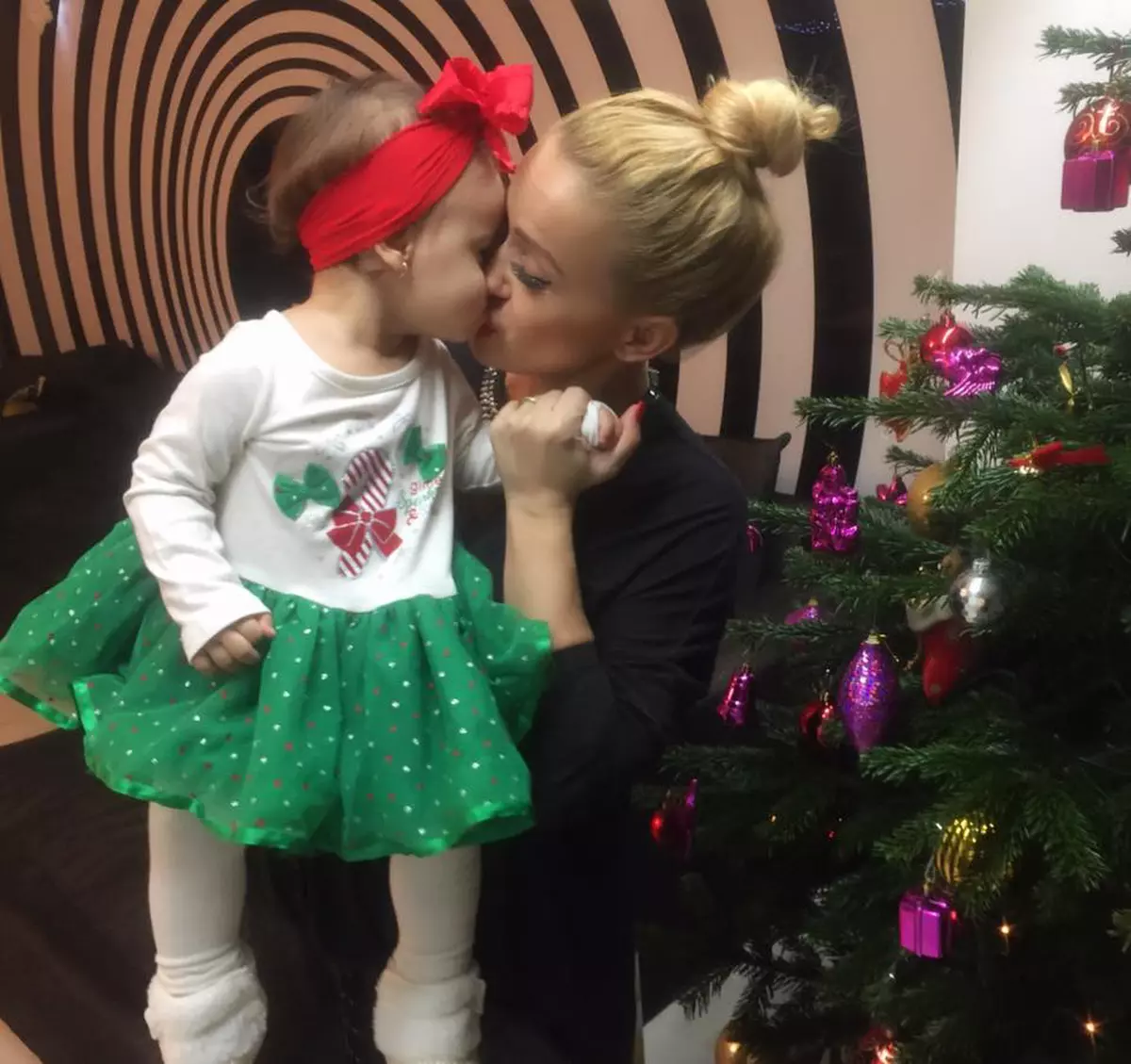 Anda Adam o sărută pe fiica, Evelin, lângă bradul de Crăciun