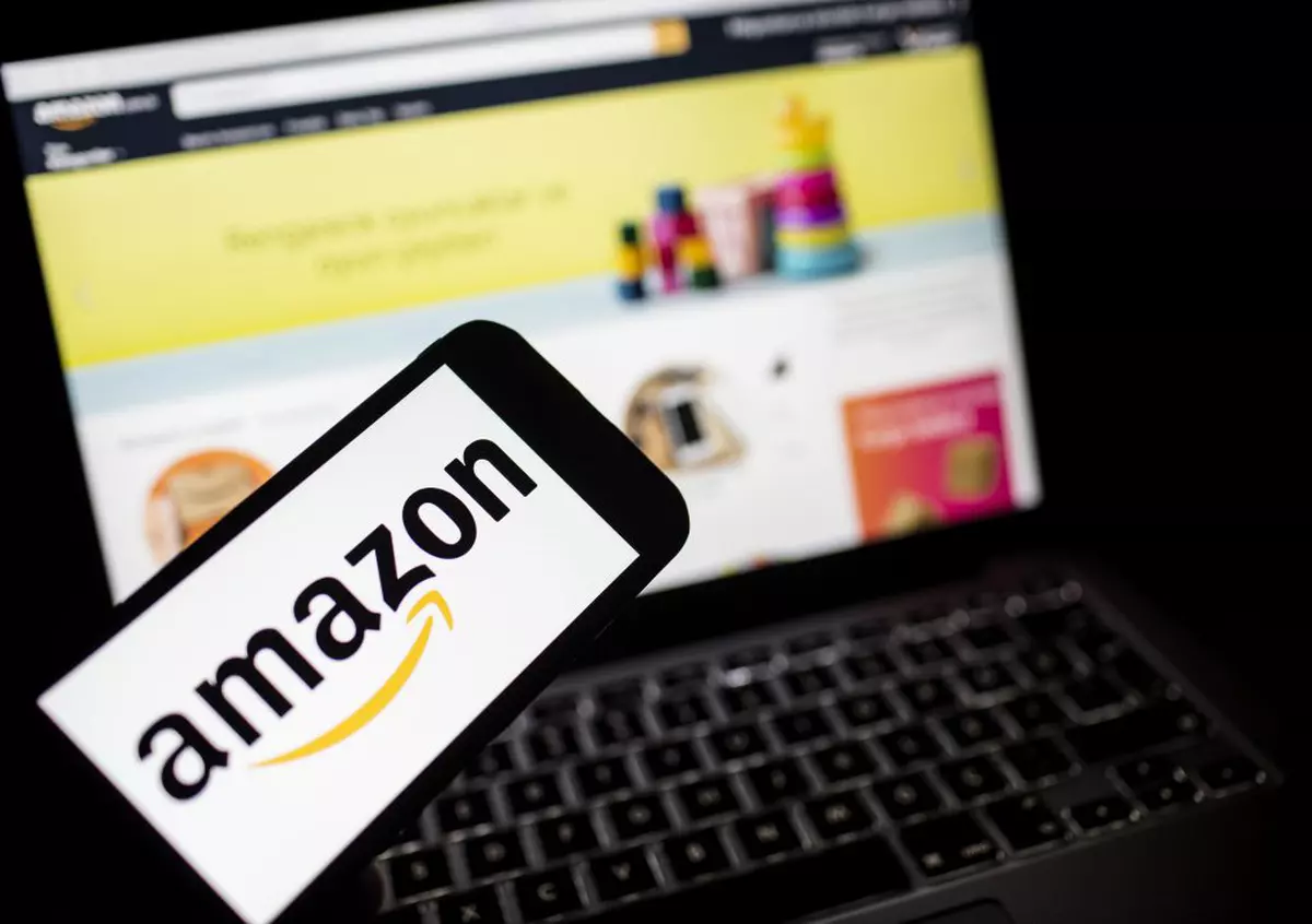 Amazon angajează 100.000 de oameni în SUA, după ce comenzile online au crescut masiv ca urmare a coronavirusului. Laptop si smartphone cu Amazon deschis