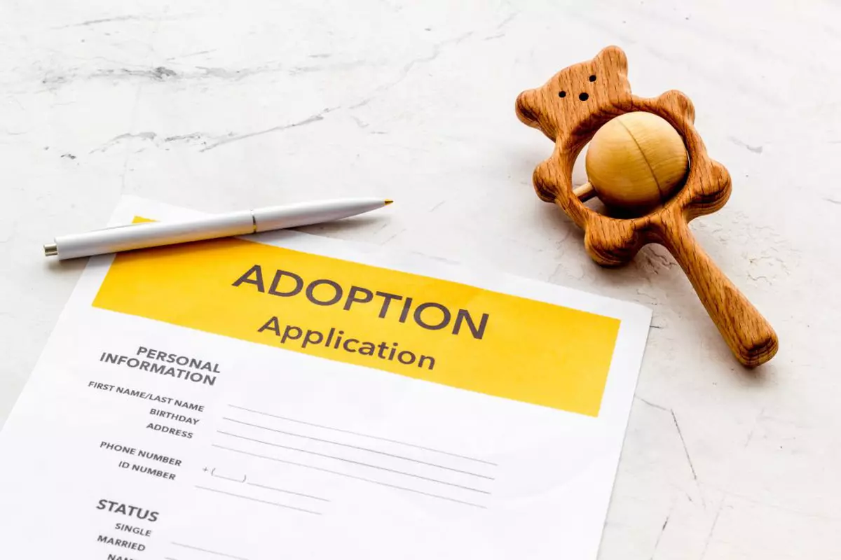 Cum poți să adopți un copil în 2022 - O jucărie de lemn, un pix şi un formular de adopţie pe o masă