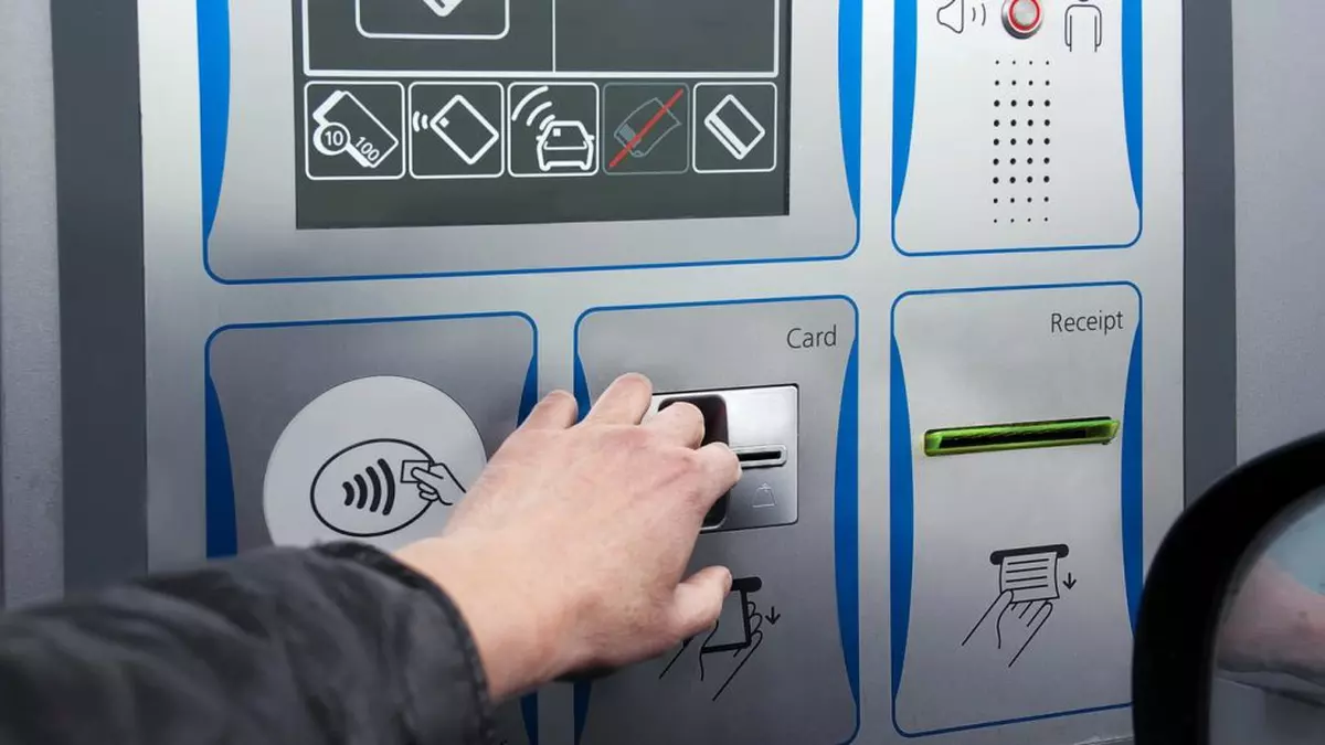 Mână de bărbat care plătește cu cardul de credit la o stație de taxare pe autostradă, fotografie în aer liber cu prim-plan neclar