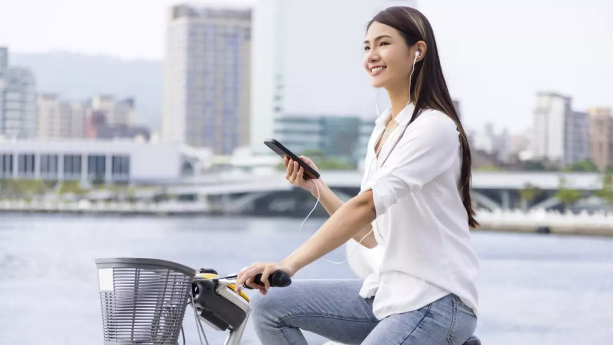 Tânără care utilizează telefonul în timp ce merge pe bicicletă