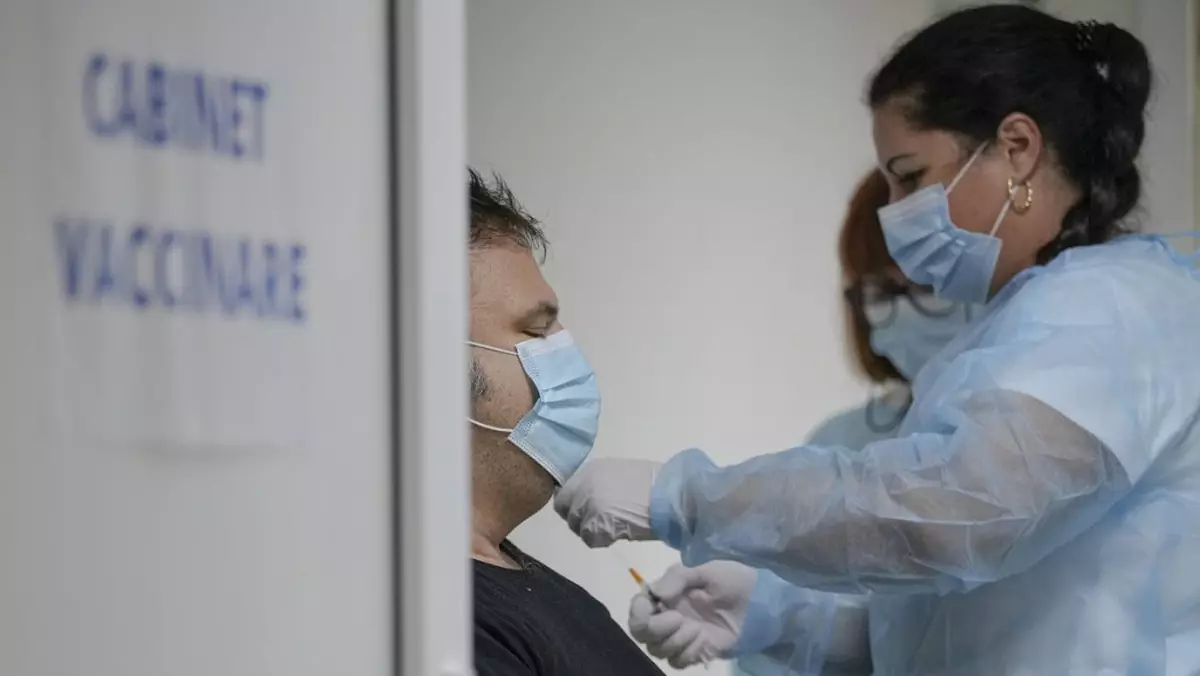 O asistentă medicală vaccinează un pacient, într-un spital