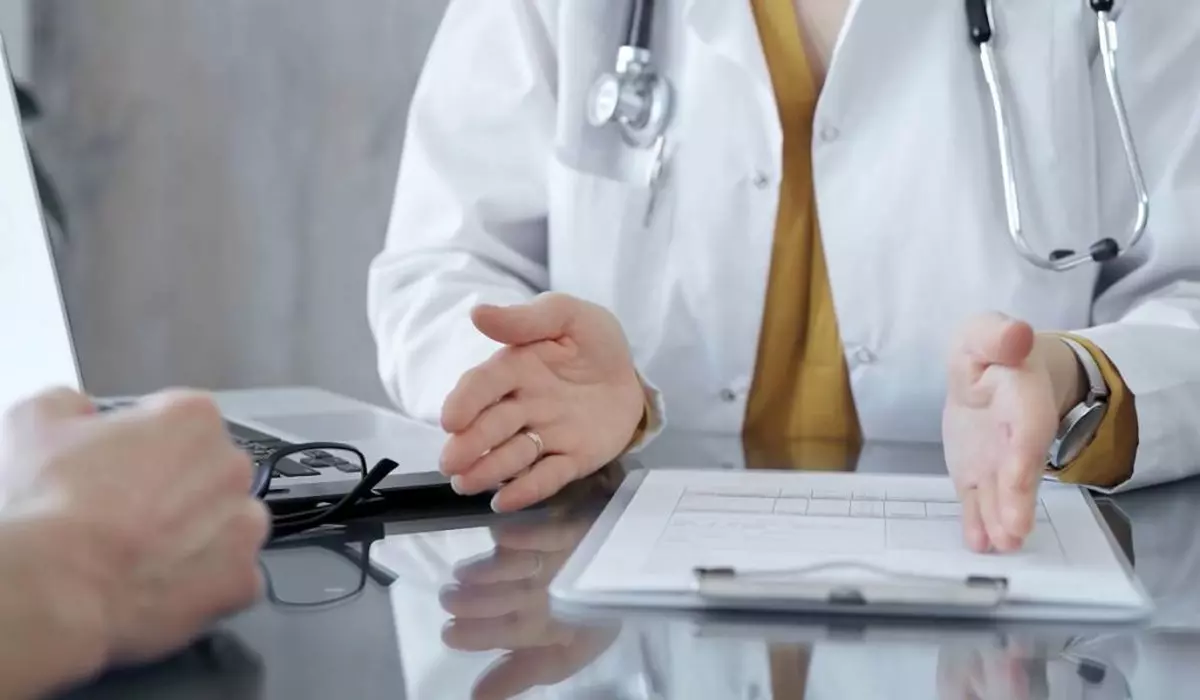 medic imbracat cu halat alb având un stetoscop la gât, discută cu un pacient