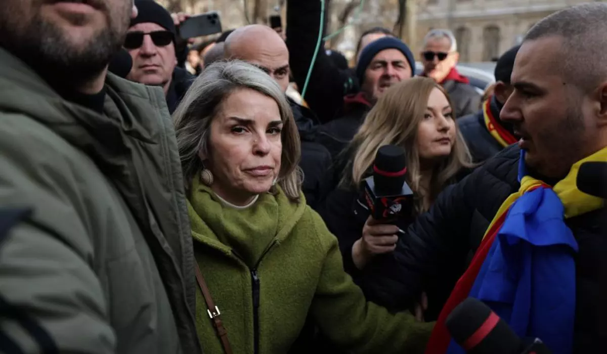 Cristela Georgescu, soția lui cătlin Georgescu, discută cu o reporteriță în fața Parchetului General. Femeia are pe ea un palton verde și este îngrijorată