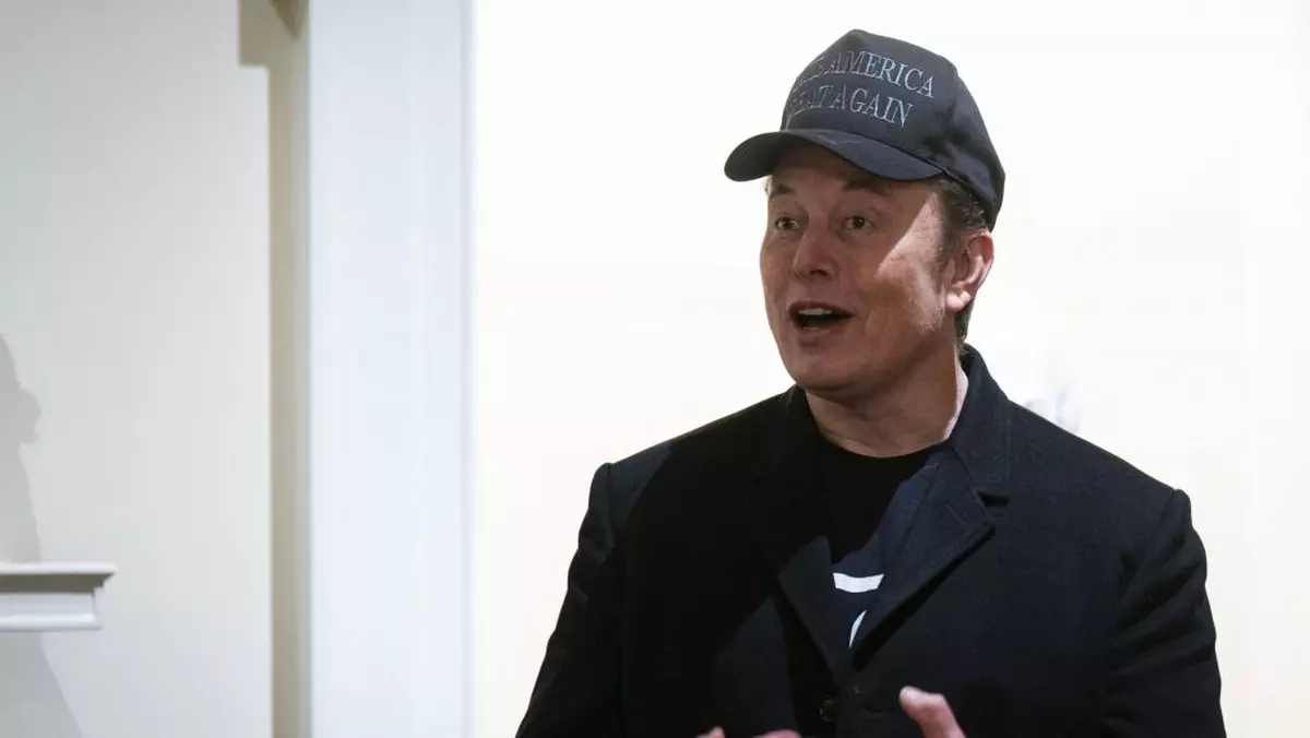 Elon Musk poartă o șapcă neagră și o jachetă,