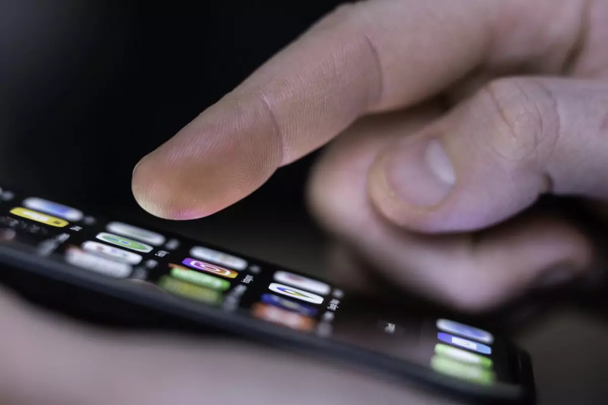 O persoană butonează pe Iphone-ul său