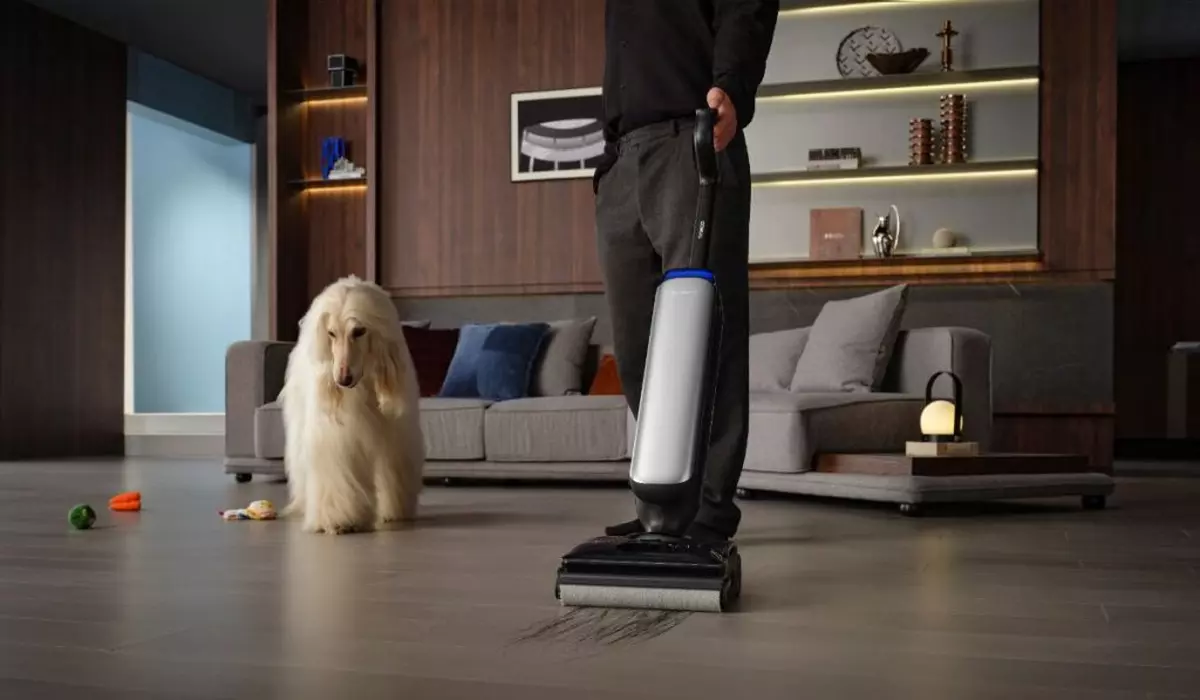 Imagine de prezentare cu un aspirator vertical Tineco, într-o sufragerie, lângă un câine.