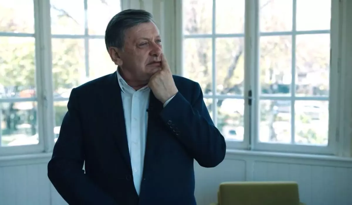 Crin Antonescu, îmbrăcat în costum și cămașă albă, fără cravată, în fața unei ferestre albe, în timp ce își ține degetul pe nas și se gândește