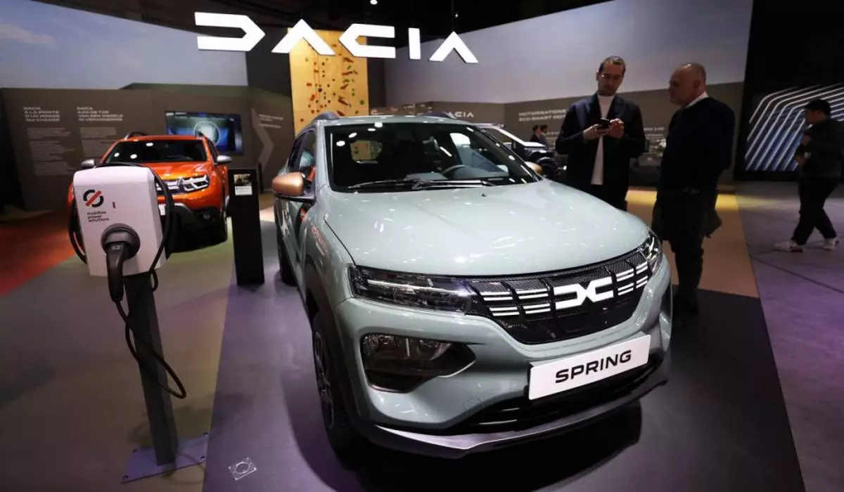 masina electrica dacia spring expusa intr-un showroom. in jurul masinii sunt cateva persoane care studiaza automobilul