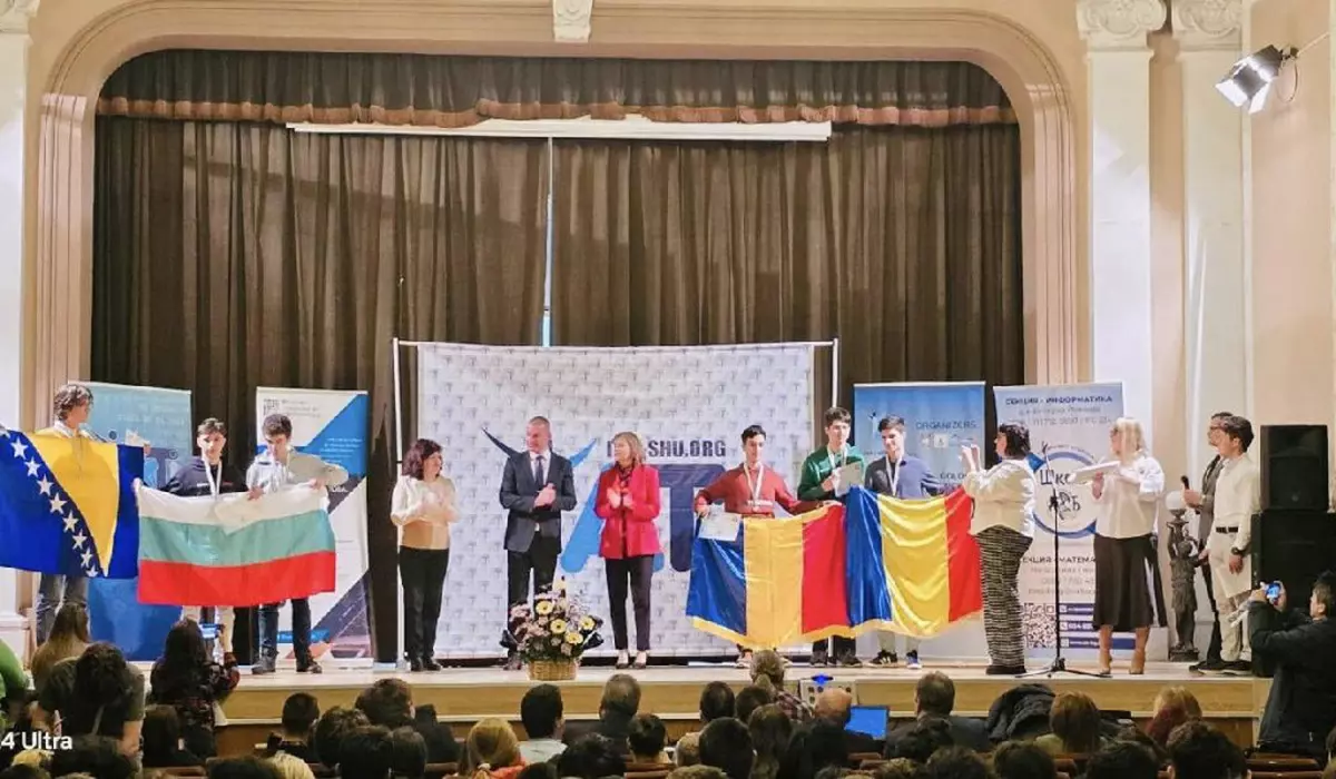 Mai mulți elevi și profesori pe o scenă, în Bulgaria, țin în mână steagurile României și Bulgariei
