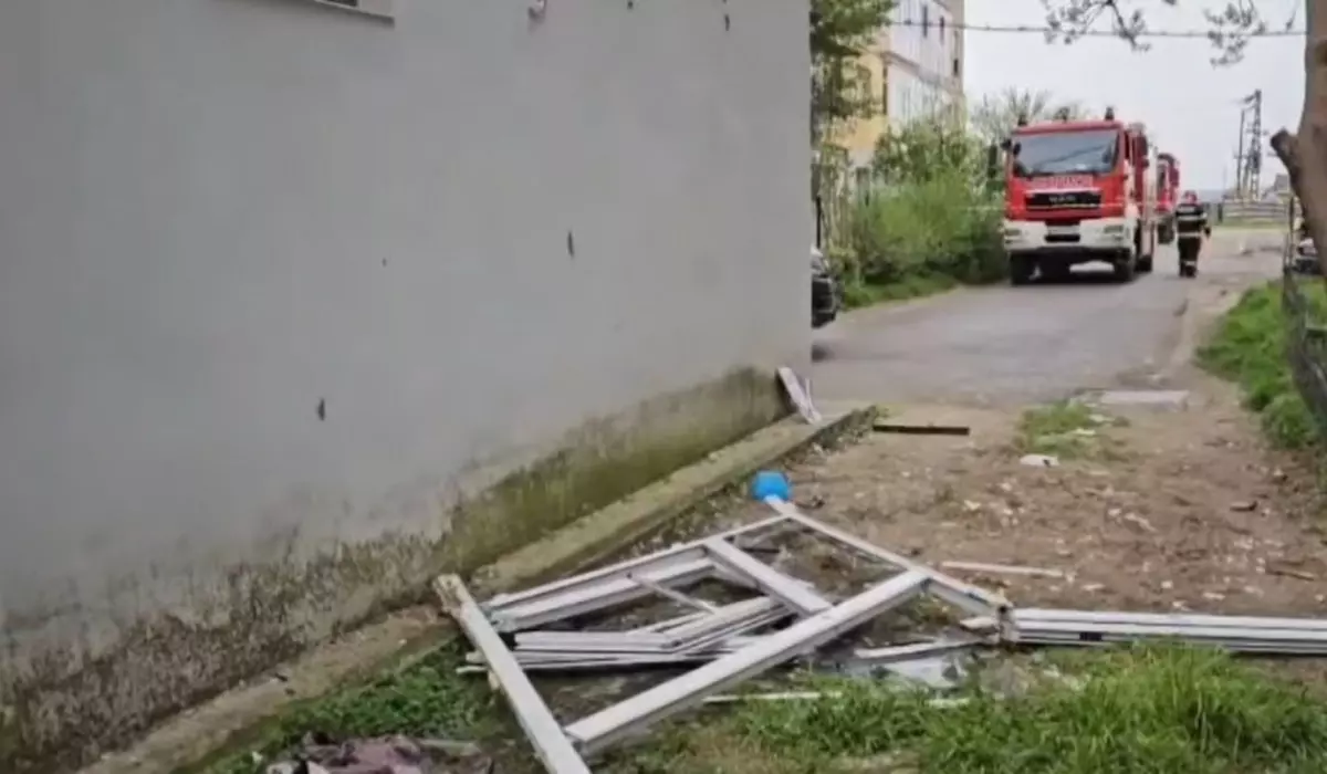 Explozie la un bloc, resturi pe jos, in fundal se vede un echipaj de intervenție al pompierilor