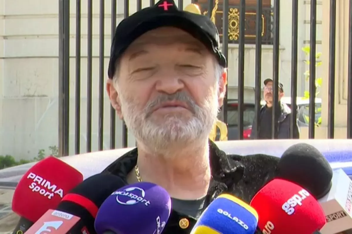 Gigi Becali dă declarații în fața palatului său din Aleea Alexandru, are mai multe microfoane de la diverse televiziuni și publicații în față.