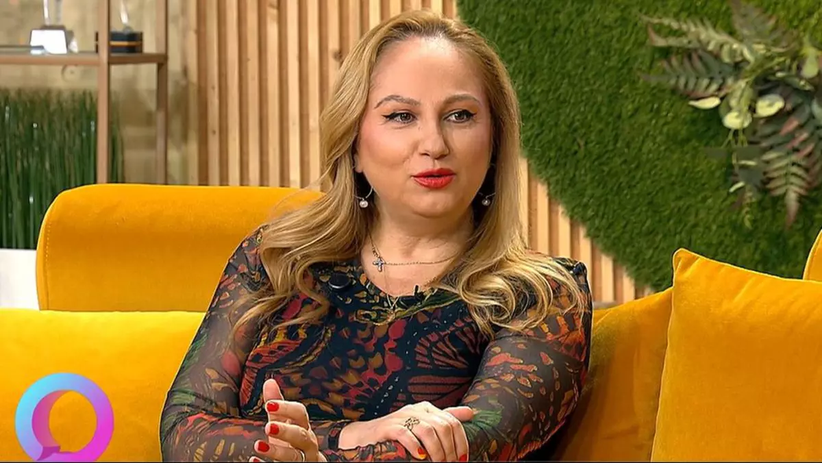 Astrologul Cristina Demetrescu, cu o bluză neagră cu desene, stă pe o canapea portocalie în studioul unei emisiuni TV, București, 14 aprilie 2025