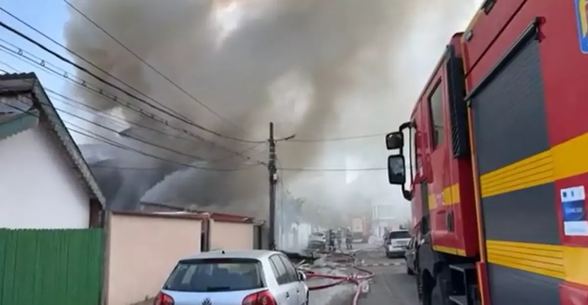 in imagine se observa o masina d epompieri care intervine la un incediu major in Bucuresti. In fundal se observa o coloana mare de fum care se ridica la cer