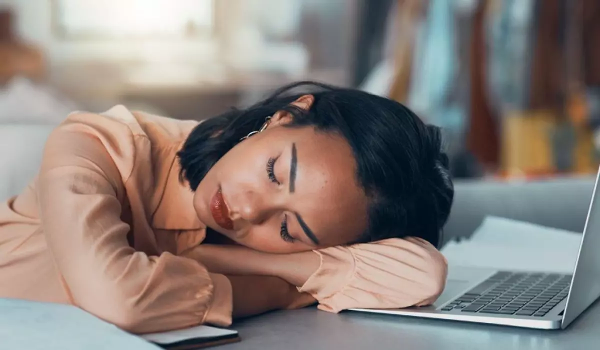 femeie obosită care doarme la job cu capul pe laptop
