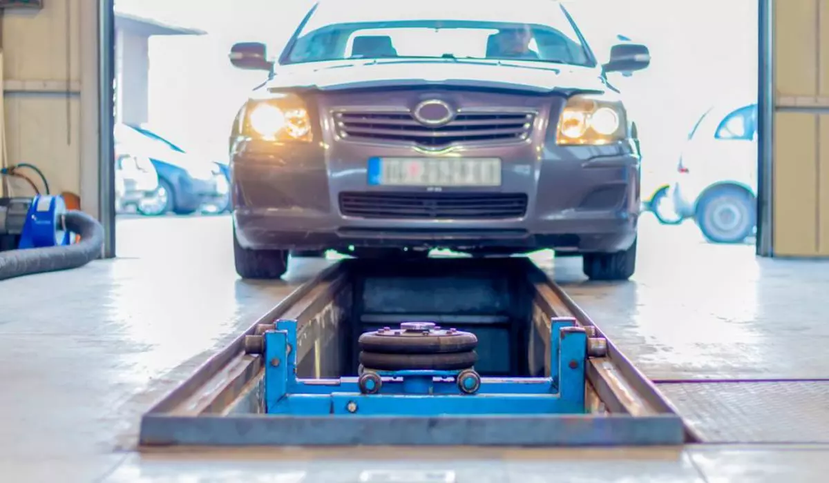 Mașină de culoare gri într-o stație ITP, poziționată deasupra unei rampe de inspecție, specifică atelierelor auto.