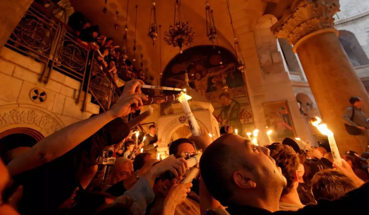 Credinciosi in biserica cu lumânări aprinse iau lumina Sfantă de PAște