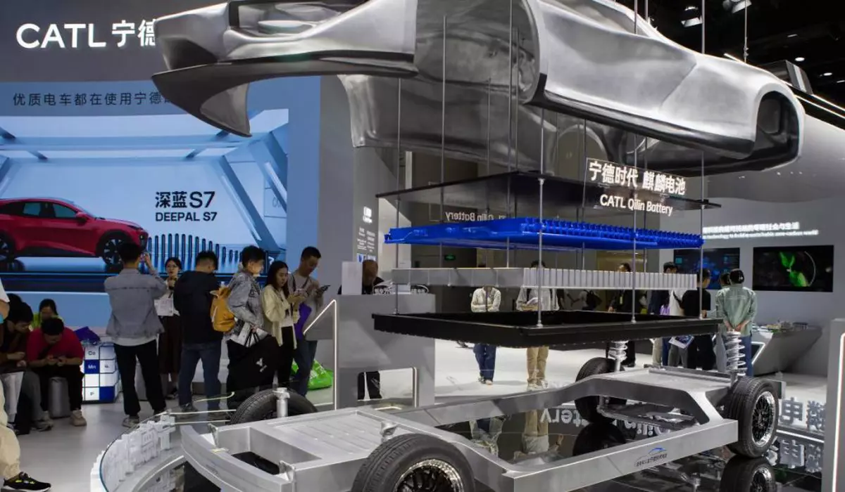 Stand de expoziție al companiei chineze CATL, lider mondial în producția de baterii pentru vehicule electrice. În prim-plan este prezentat un model demonstrativ al unui șasiu de mașină electrică. Pe fundal vizitatorii expoziției privesc panouri informative și reclame