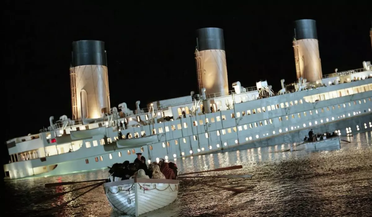 o scena de film cu un vas care se scufunda pe apa, cu o braca de salvare plina cu oameni