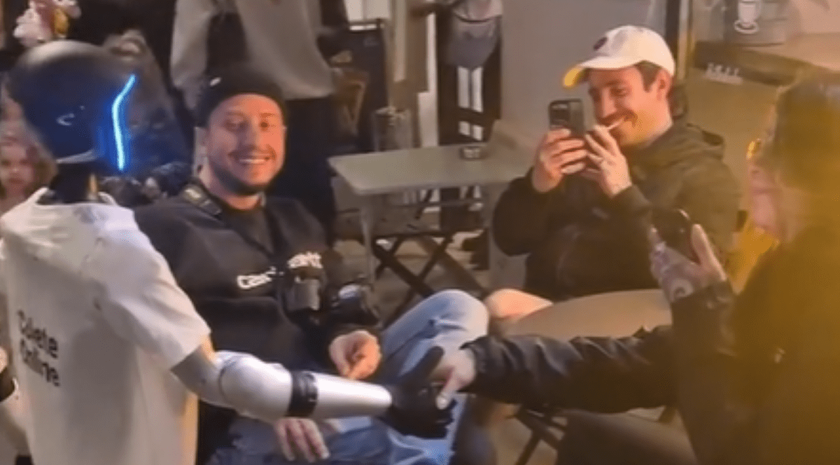 Robotul umanoid surprins în timp ce dă mâna cu o persoană aflată pe terasă