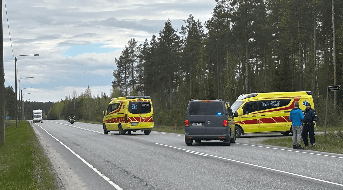 Două ambulanțe galbene și o mașina de politie pe o seosea. două persone stau de vorba langa un indicator