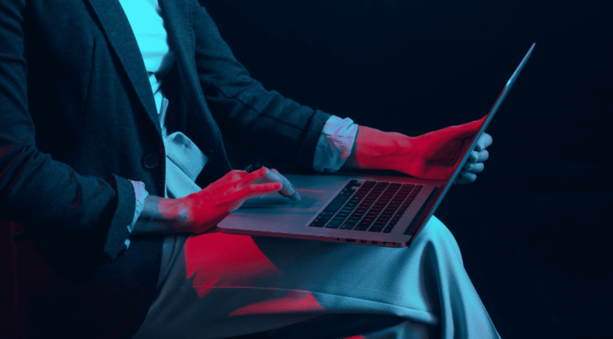 Femeie imbracata elegant, tine in poala un laptop pe care il foloseste