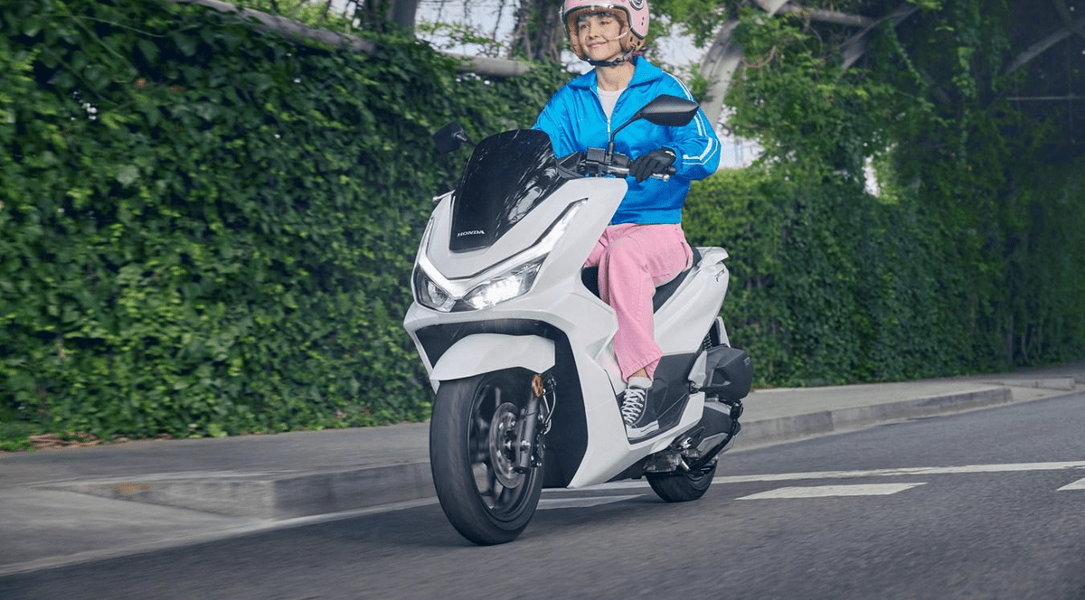 Femeie tanara pe scuter alb Honda de 125 cm