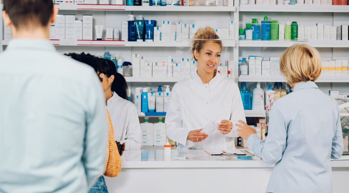 Catena - femeie farmacista vorbind cu clientul, o doamna blonda.