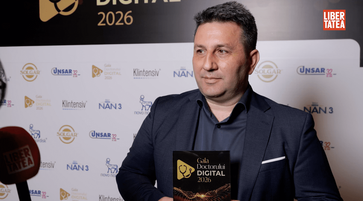 Dr. Ștefan Tucă, medic primar chirurgie generală, la Gala Doctorului Digital 2026, îmbrăcat cu o cămașă neagră și un sacou negru, cu un premiu în mână, pe un fundal cu un panou alb și nergu.