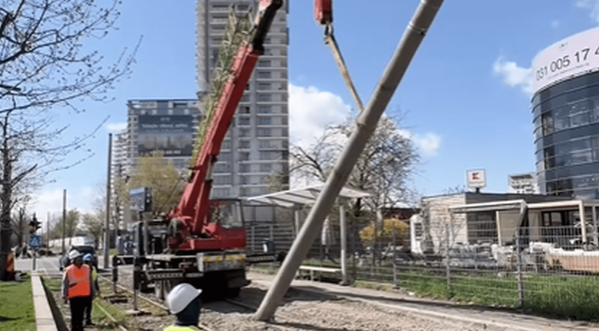 Un stâlp de beton este dat jos cu o macara pe linia de tramvai din Pipera, București, aprilie 2026