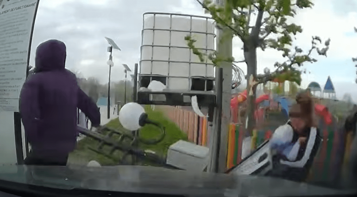 Un bărbat cu glugă pe cap trece pe lângă un stâlp care cade doborât de furtună și lovește o femeie ce ținea în brațe un bebeluș