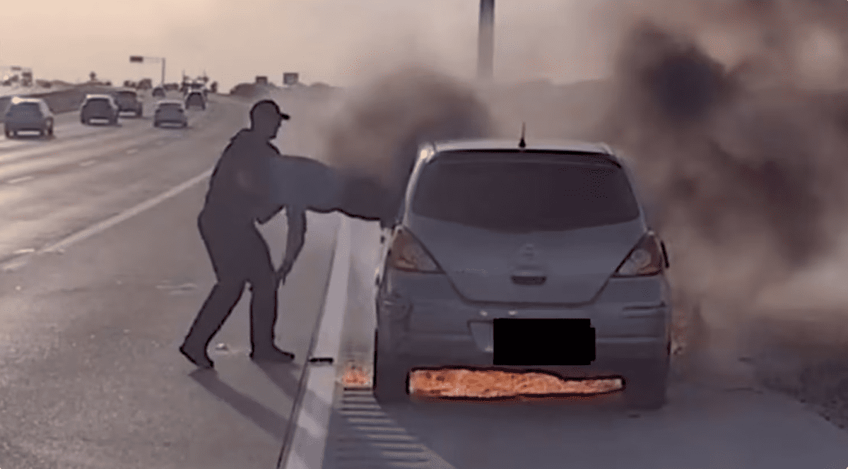 Un polițist scoate un șofer pe geamul portierei, după ce mașina a luat foc pe o autostradă din Texas, iulie 2026