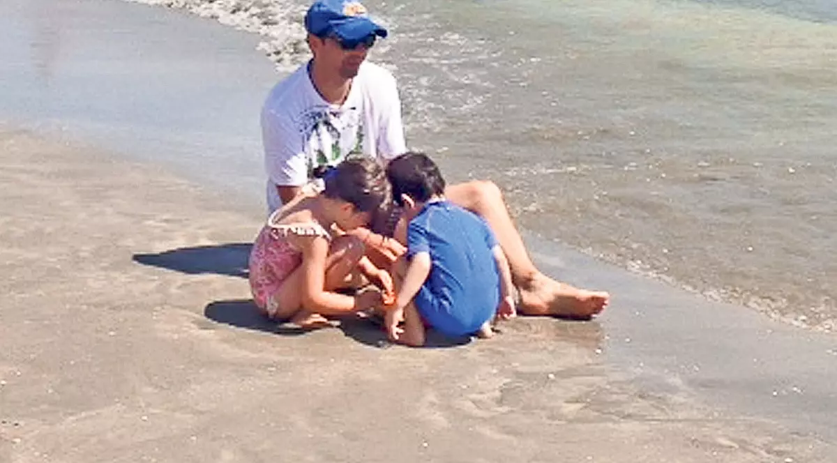 Negru se joacă cu maşinuţa în nisip, pe litoral