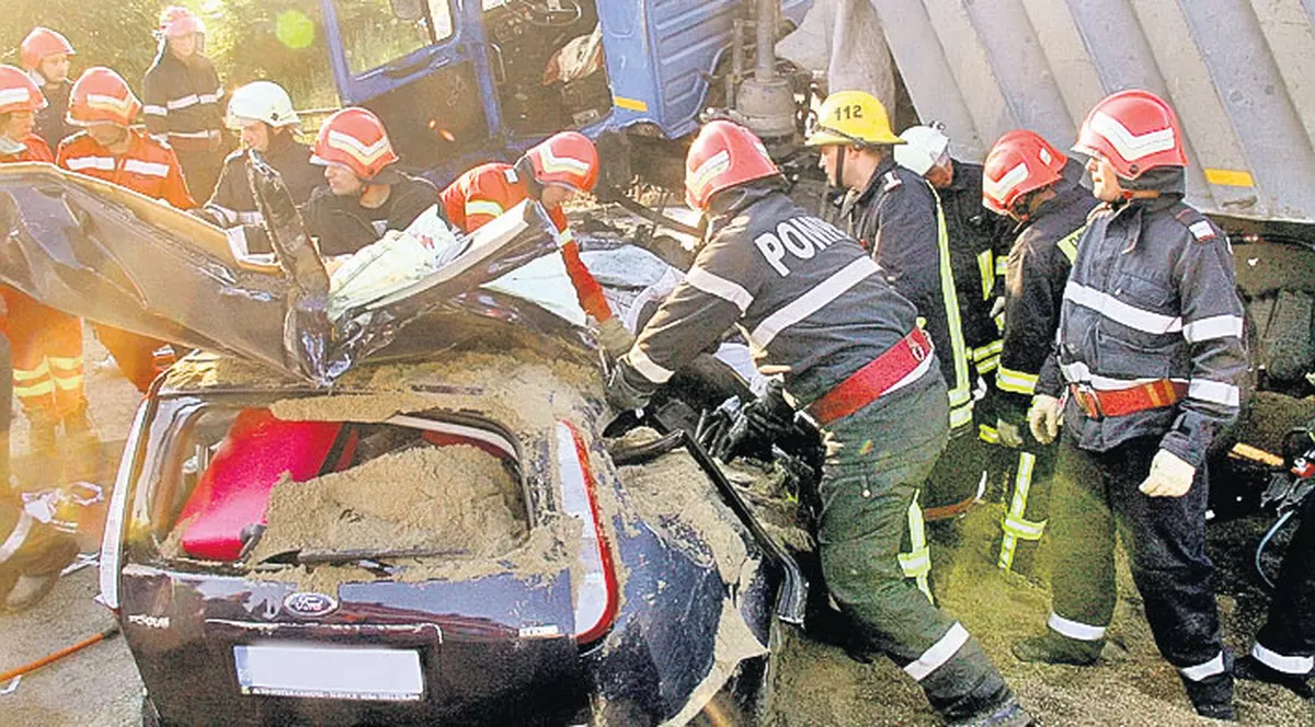 Striviți sub tone de nisip | Patru angajați ai unei firme din Craiova au ajuns cu autoturismul sub un camion