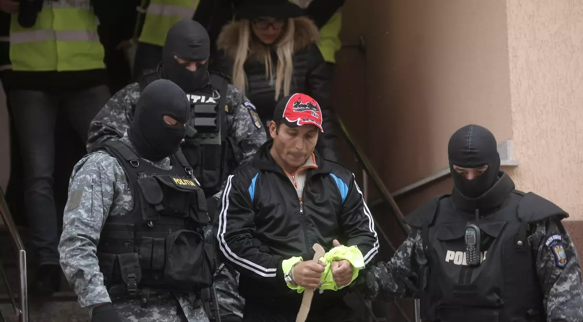 ionel ionescu înarmat cu un cutit din lemn, încadrat de mascati