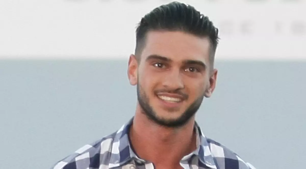 Dorian Popa, îmbrăcat în cămașă în carouri, afișează un zâmbet larg pe față