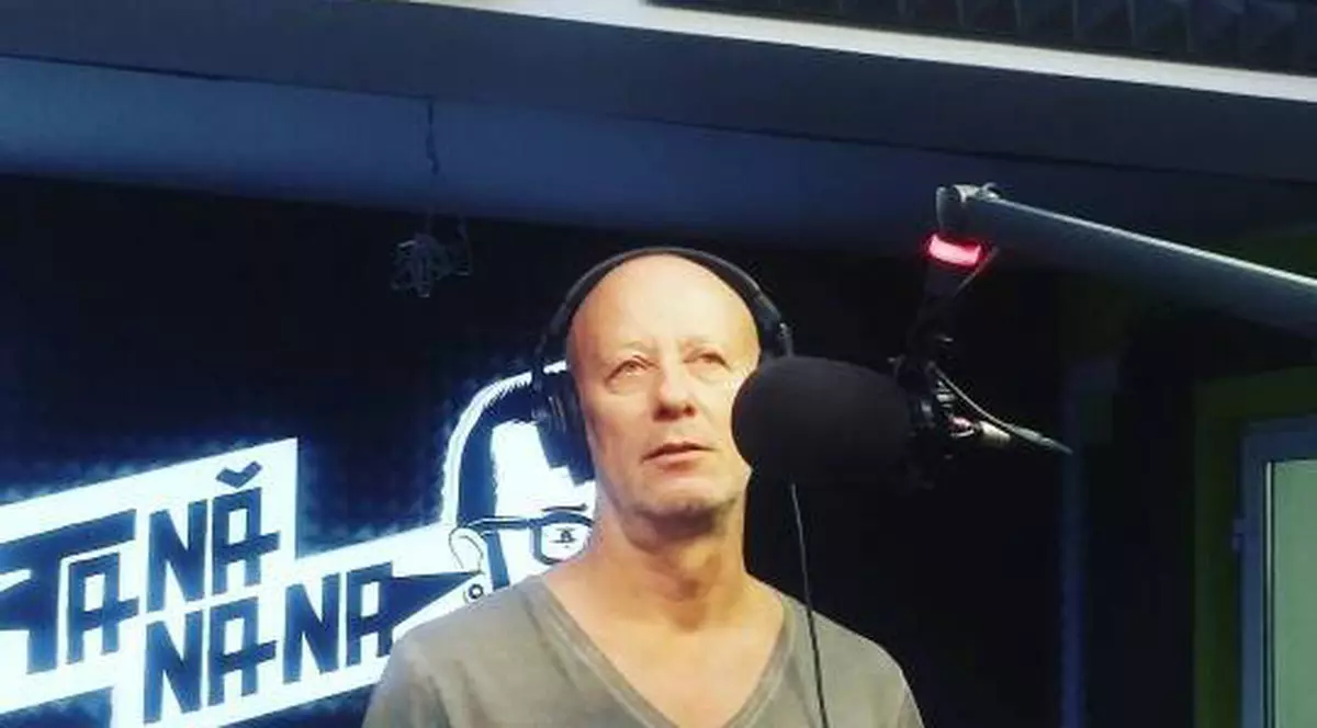 Andrei Gheorghe, cu căștile pe urechi, vorbește la microfon, într-un studio radio