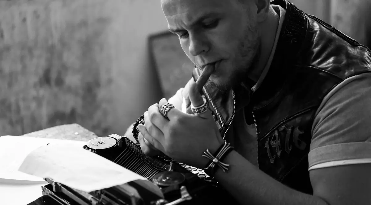 Codin maticiu stă la o masă și își aprinde un trabuc