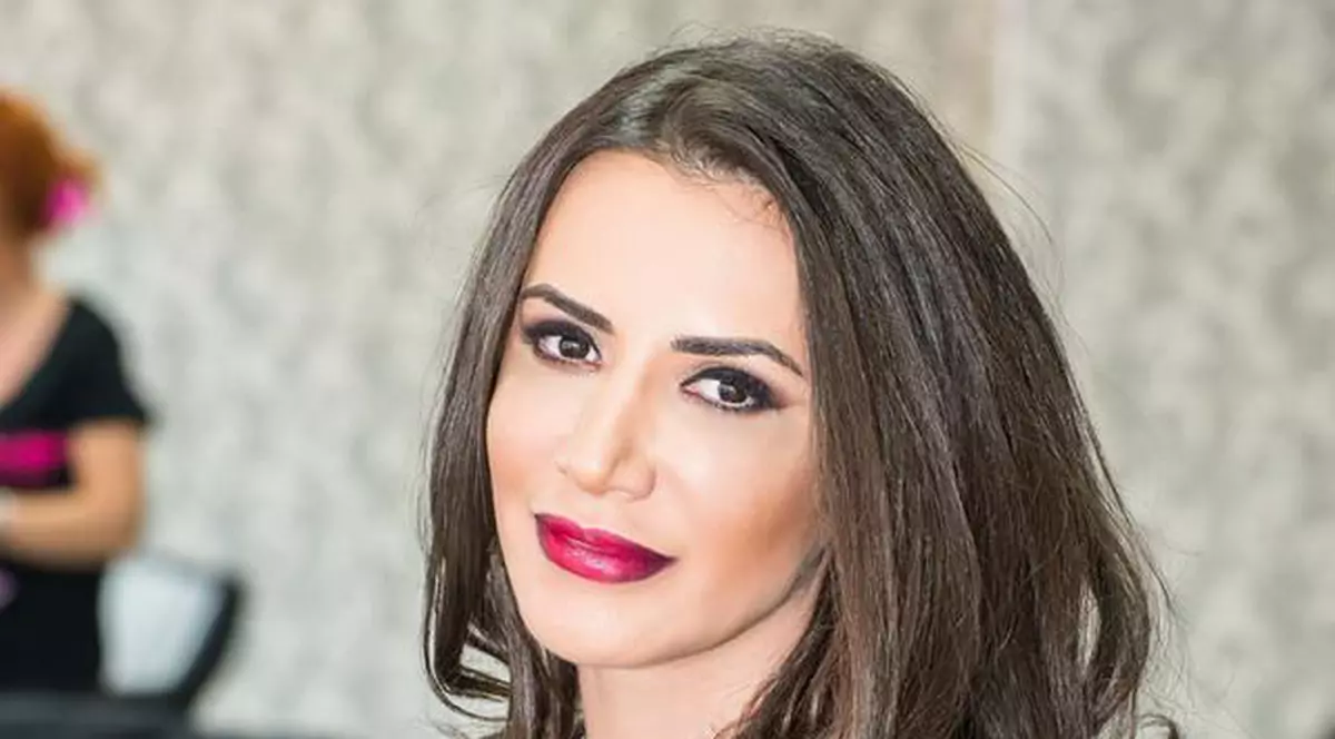 Mara Bănică, așezată pe un scaun, zâmbește