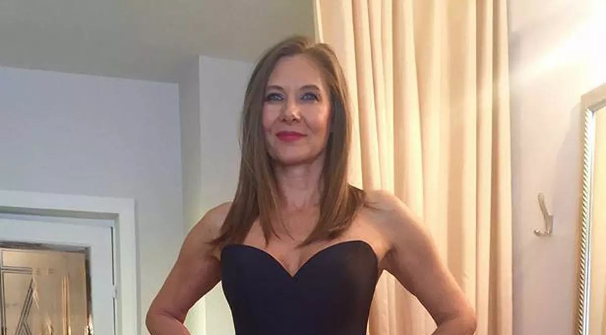 Romania Iovan, într-o rochie de seară de culoare neagră, cu părul lăsat pe spate, pozează în atelierul unei creatoare de modă