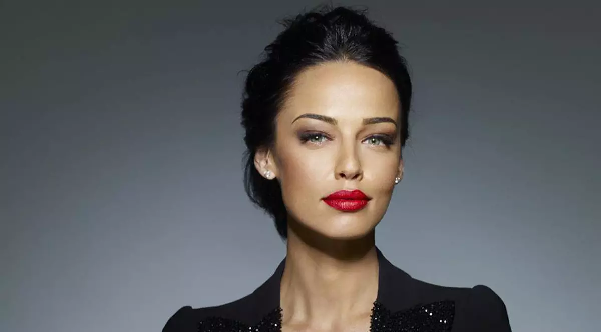 Andreea raicu, într-o rochie neagră cu decolteu adânc, stă cu mâinile împreunate