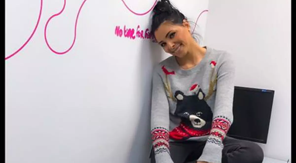 Corina Caragea stă sprijinită de un perete și zâmbește