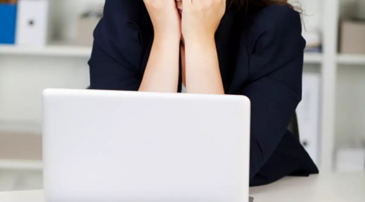 Sindromul burnout, asasinul tăcut de la muncă. Angajată în fața unui calculator cu mâinile la ochi