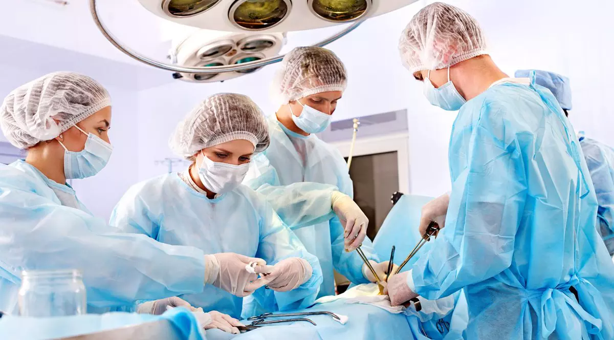 Mai mulți medici operează un pacient, într-o sală de operații