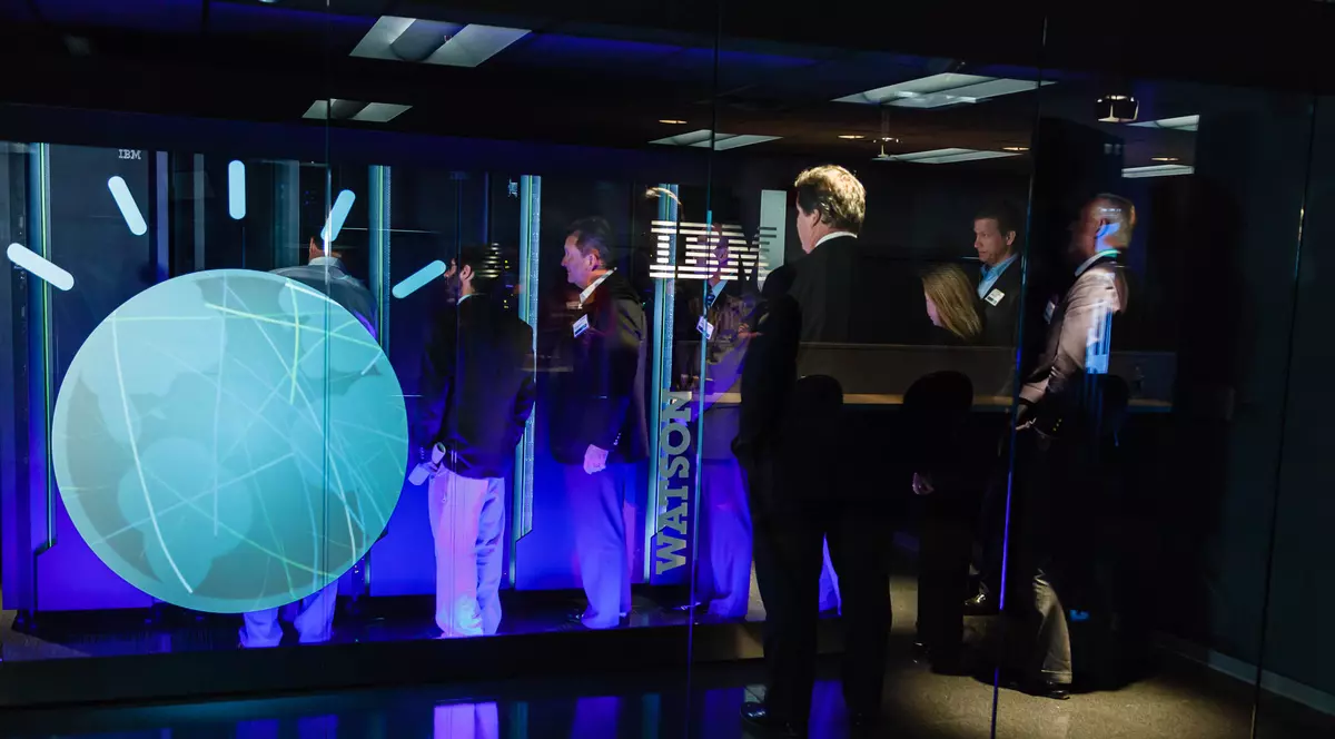IBM dezvoltă în România antiviruși pentru mașini, bazați pe inteligența artificială. Mai mulți oameni stau în fața supercomputerului Watson