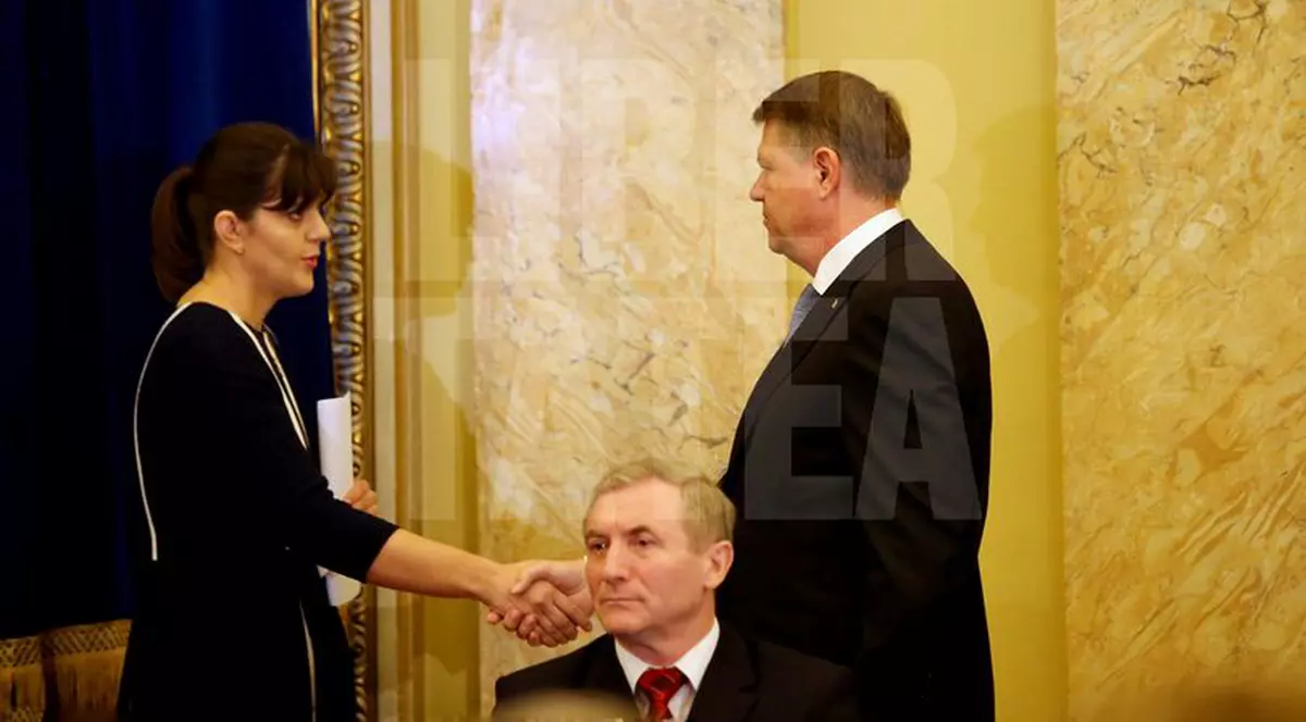 Ce scrie presa internaţională despre revocarea lui Kovesi. Iohannis și Kovesi stau la o masă de prezidiu, la o întâlnire de lucru comună. Klaus Iohannis dă mâna cu Laura Codruța Kovesi, stând în picioare. În fața lor, pe un scaun, stă Augustin Lazăr - Procrurorul General al României