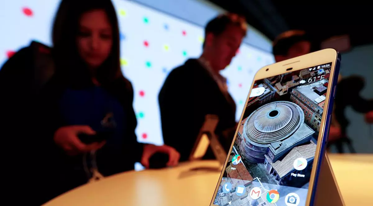 Google lucrează la un Pixel mai ieftin, destinat țărilor în curs de dezvoltare, precum India. Acesta va fi lansat în vară. Google Pixel fotografia pe masă, cu două persoane pe fundal