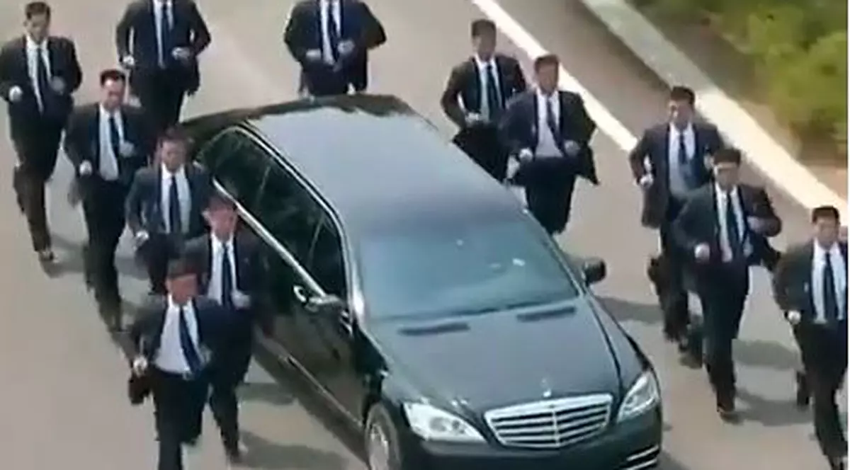 mulți bodyguarzi aleargă pe lângă mașina lui Kim Jong-un