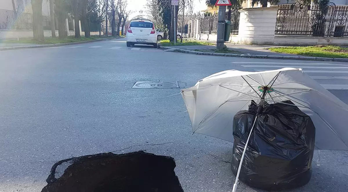 Un crater pe o stradă din centrul Timișoarei, semnalizat cu o umbrelă